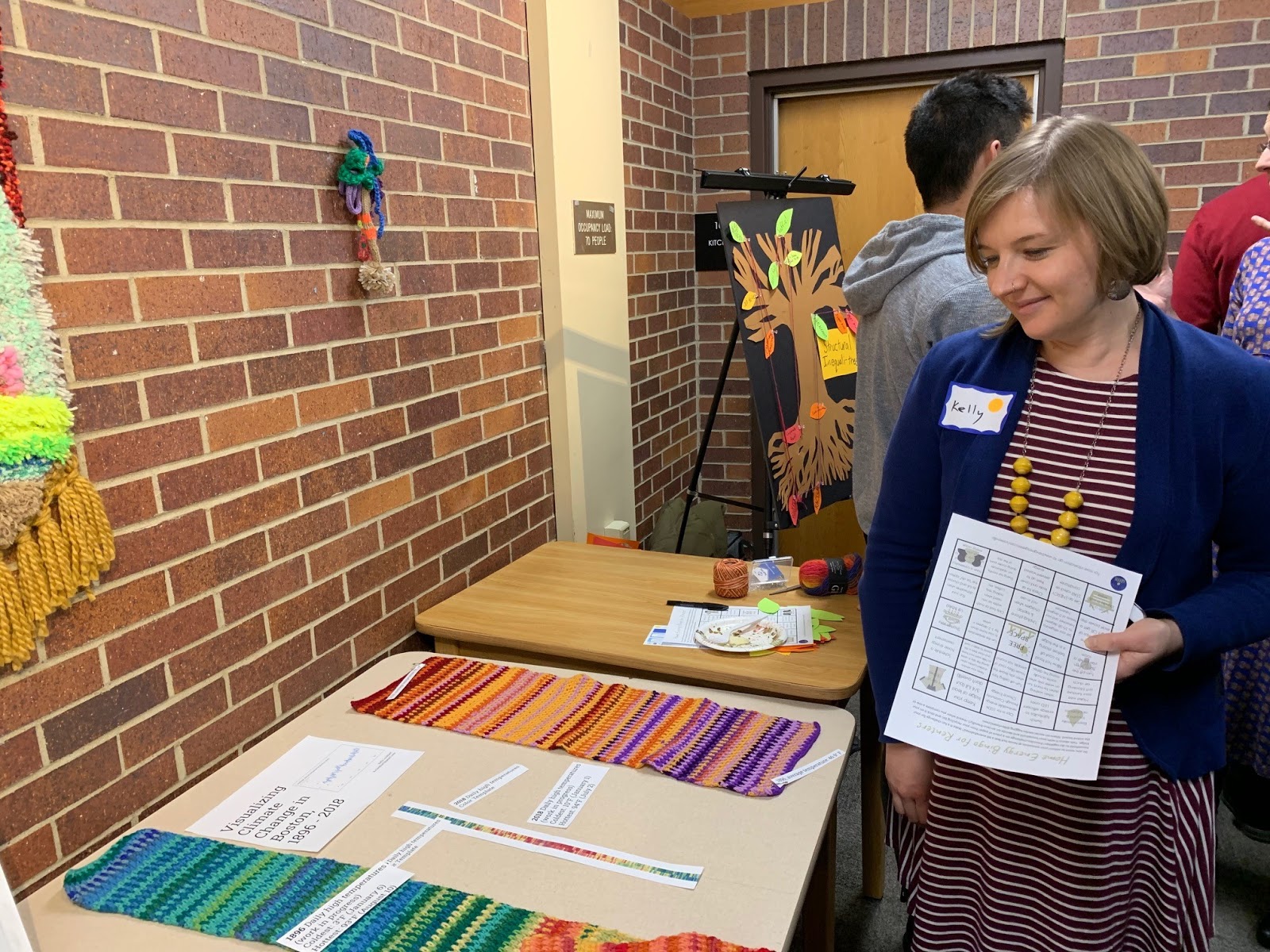 SHS student stands next to her crochet project, showing colorful temperature changes over time