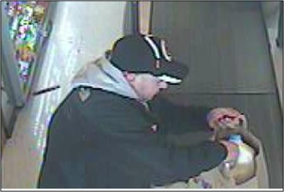 Suspect is seen at checkout, appearing to be light-skinned, bald, and heavyset, wearing black athletic pants, black jacket over gray hoodie, and a black ball cap.