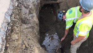 Workers access an underground sewer pipe